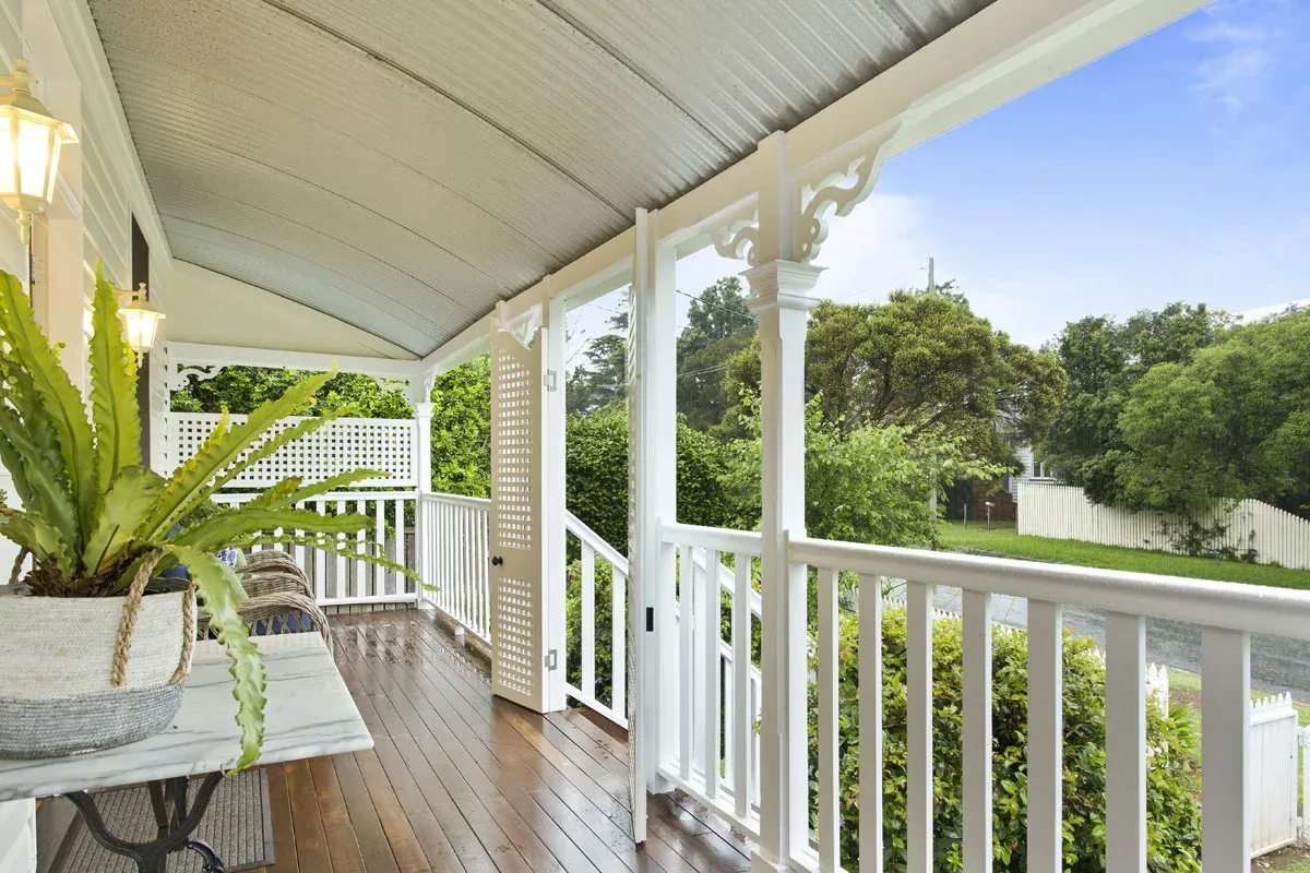 a veranda with a white railing and a potted plant on it .
