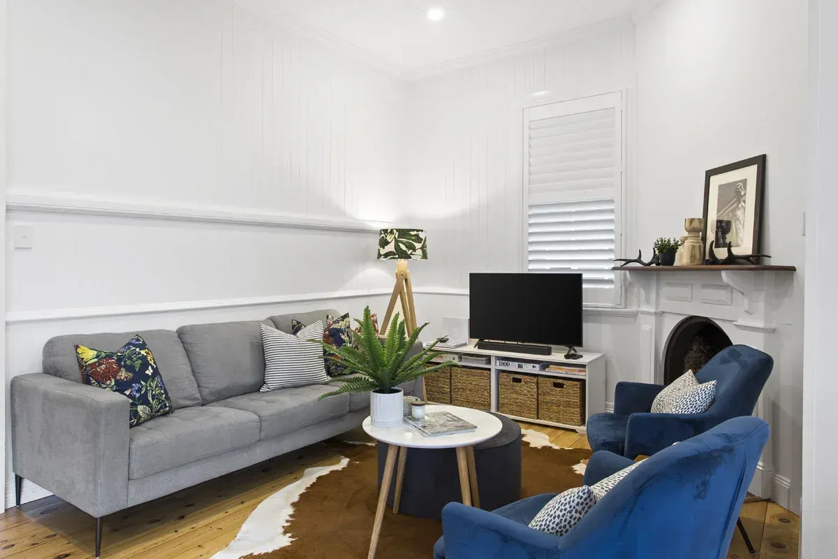 a living room with a couch , chairs , table and television .