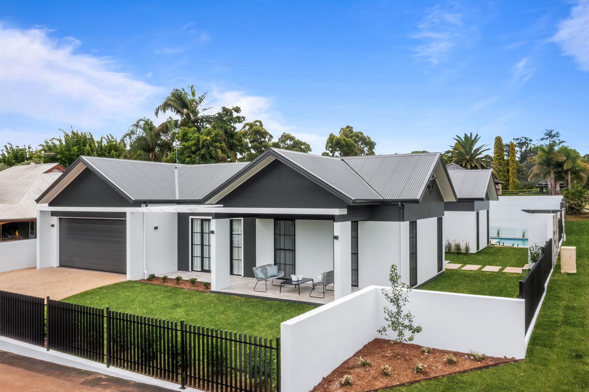 A black and white house with a black fence in front of it.