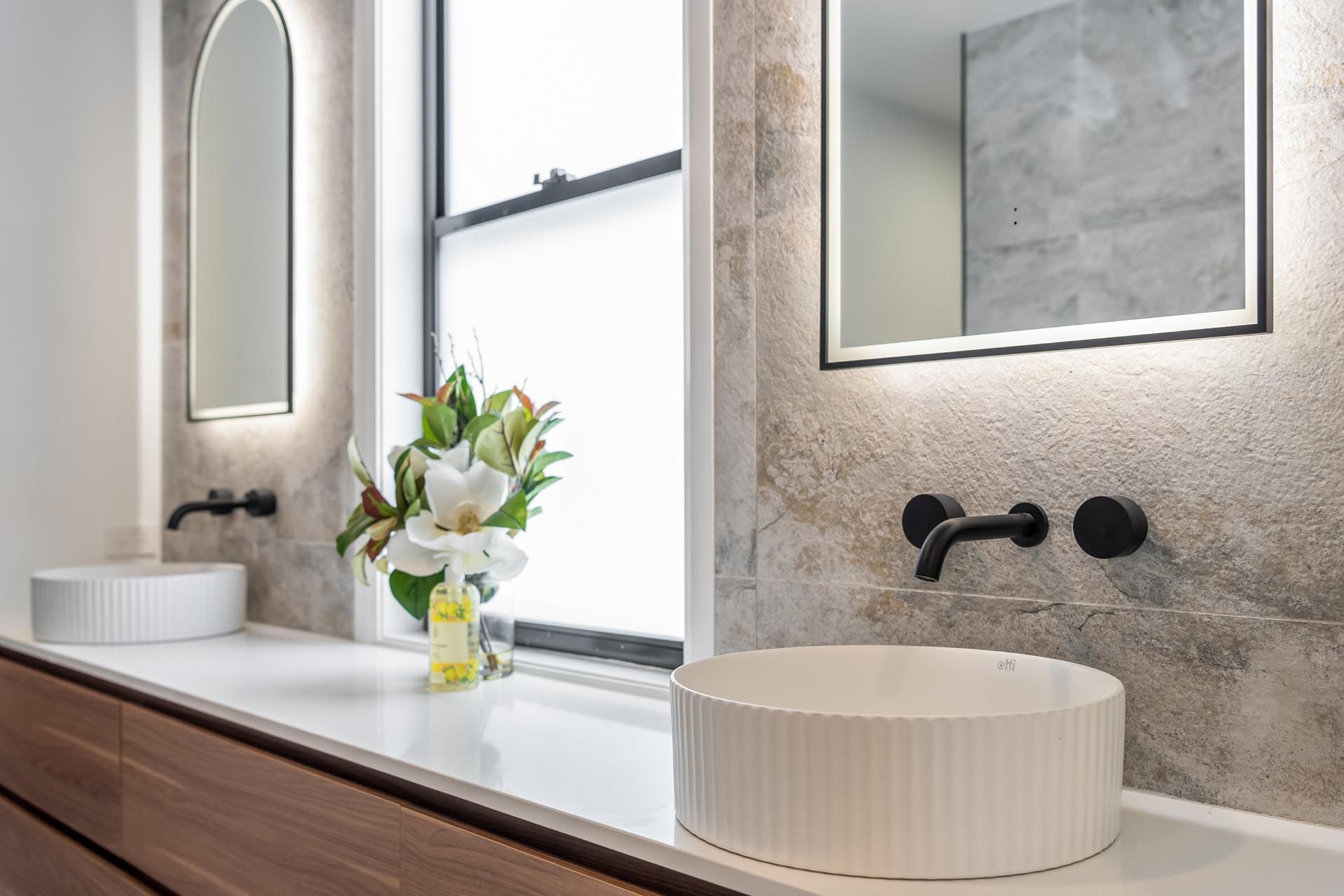 A bathroom with two sinks , a mirror and a window.