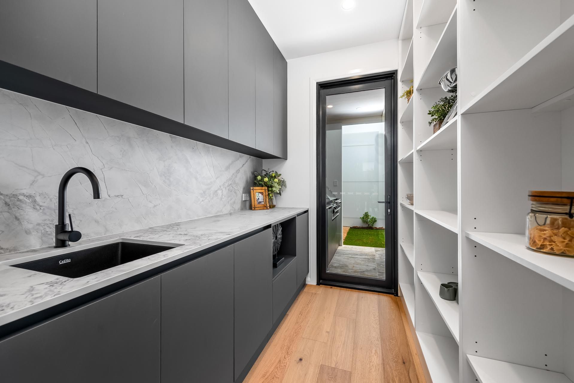 A kitchen with a sink , shelves and a mirror.