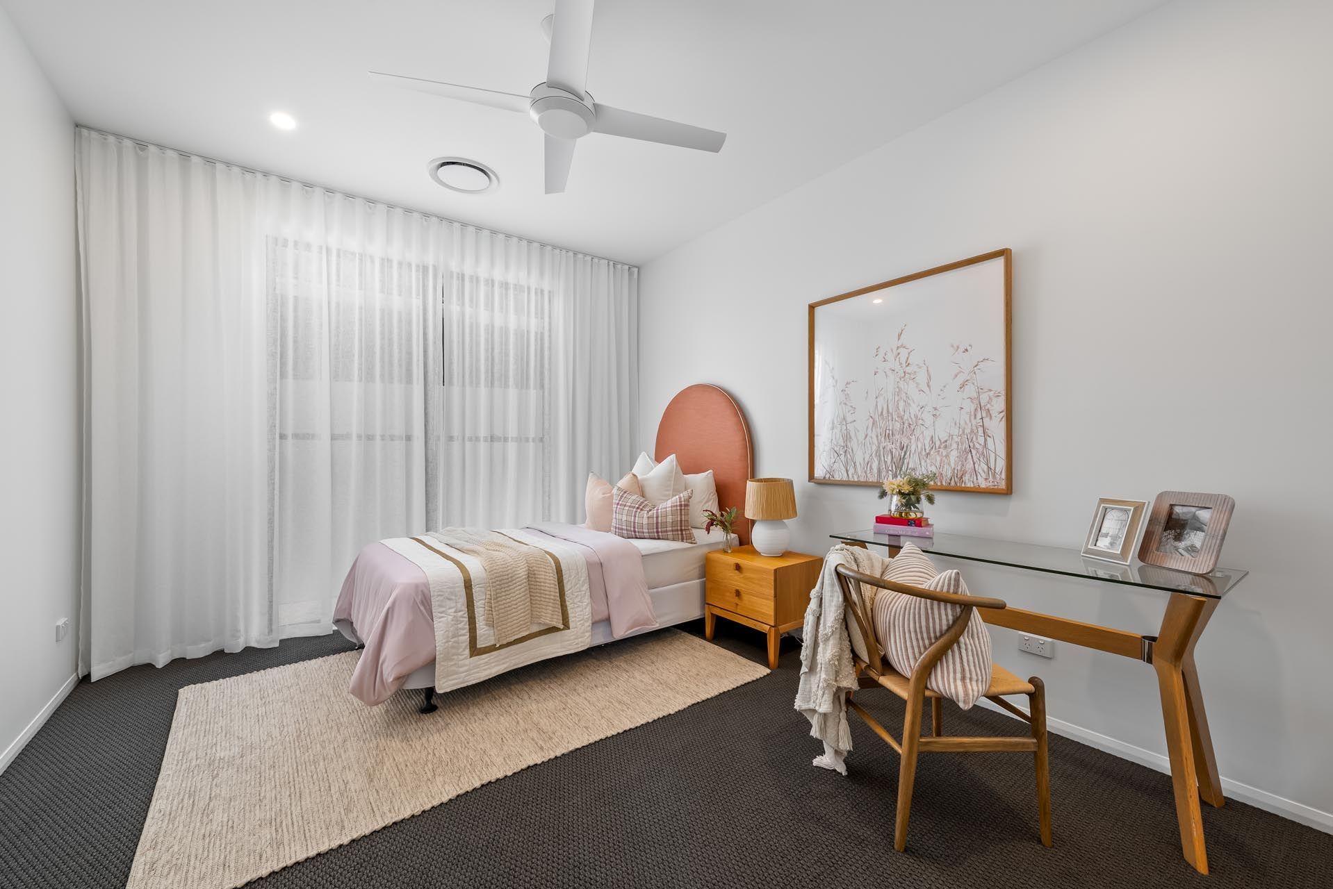 A bedroom with a bed , desk , chair and ceiling fan.