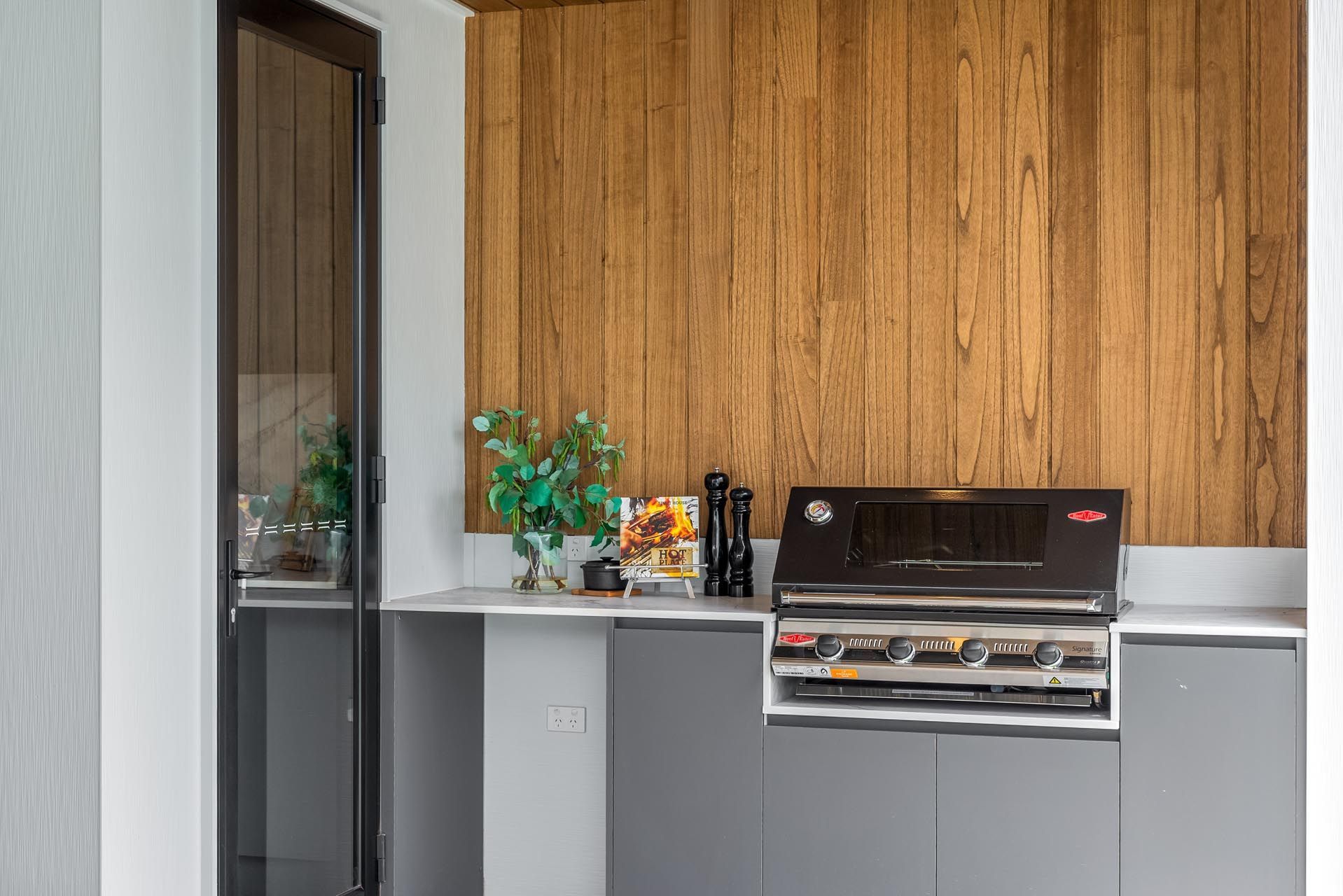 An outdoor BBQ area with a grill and a refrigerator.