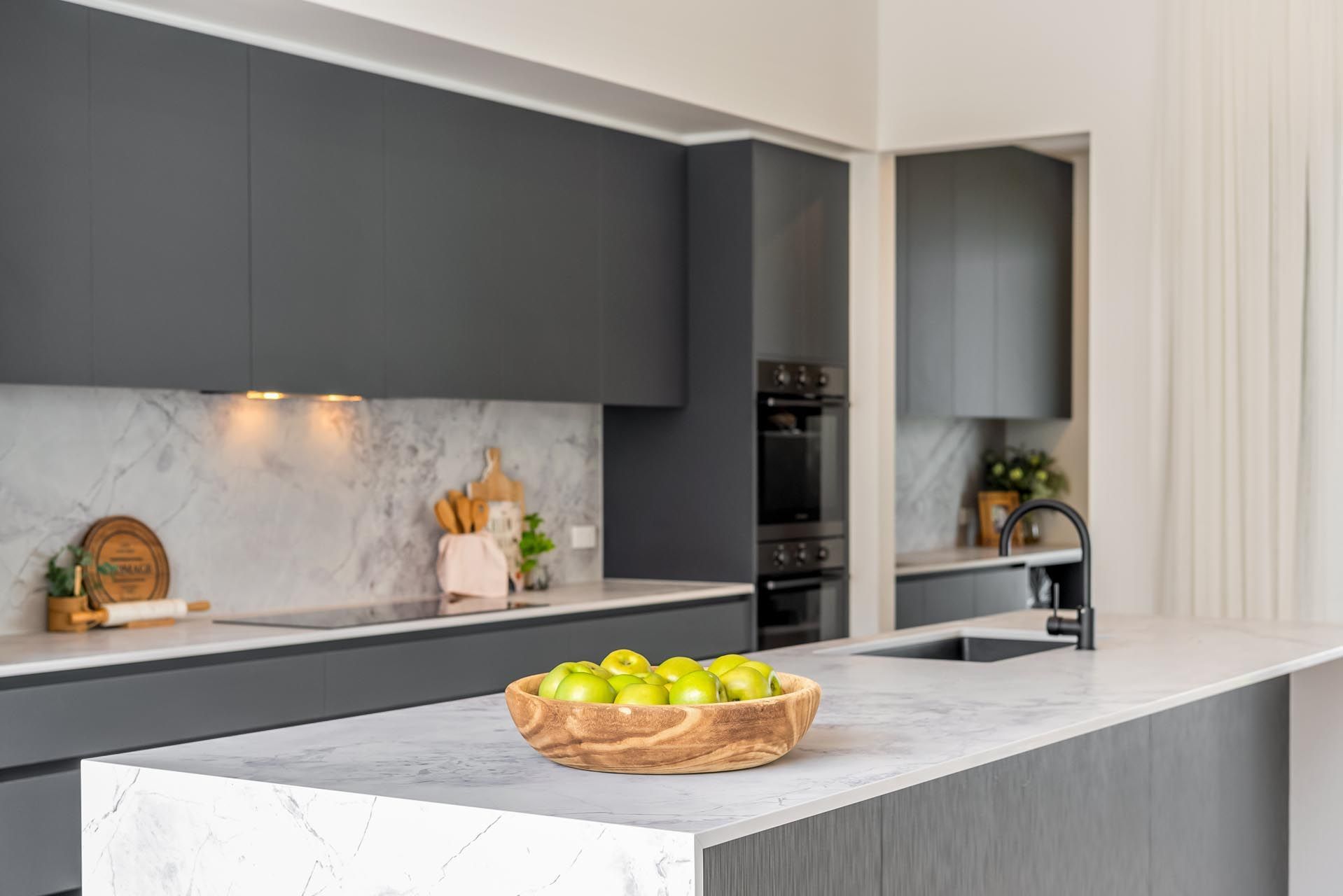 A kitchen with a bowl of apples on the counter.