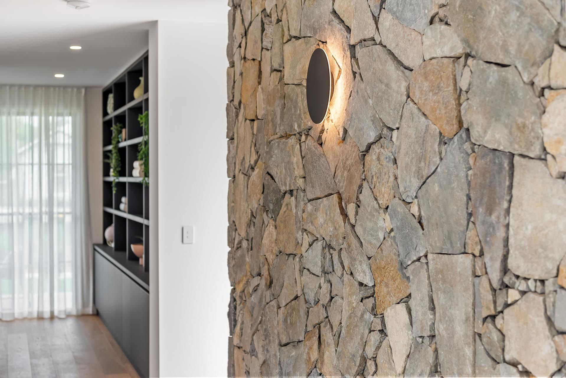 A living room with a stone wall and a light on the wall.