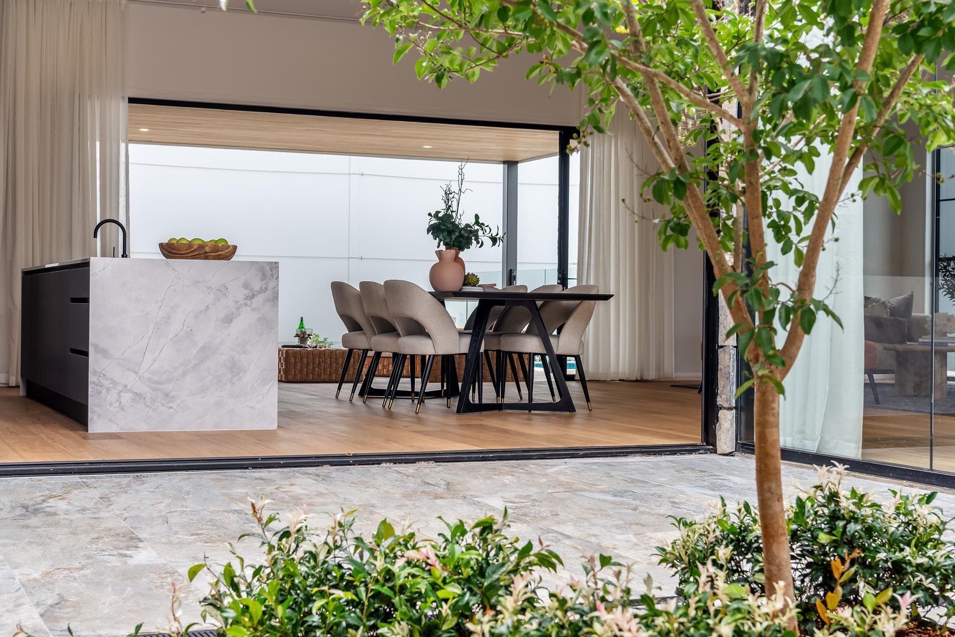 A kitchen and dining room with a tree in the foreground