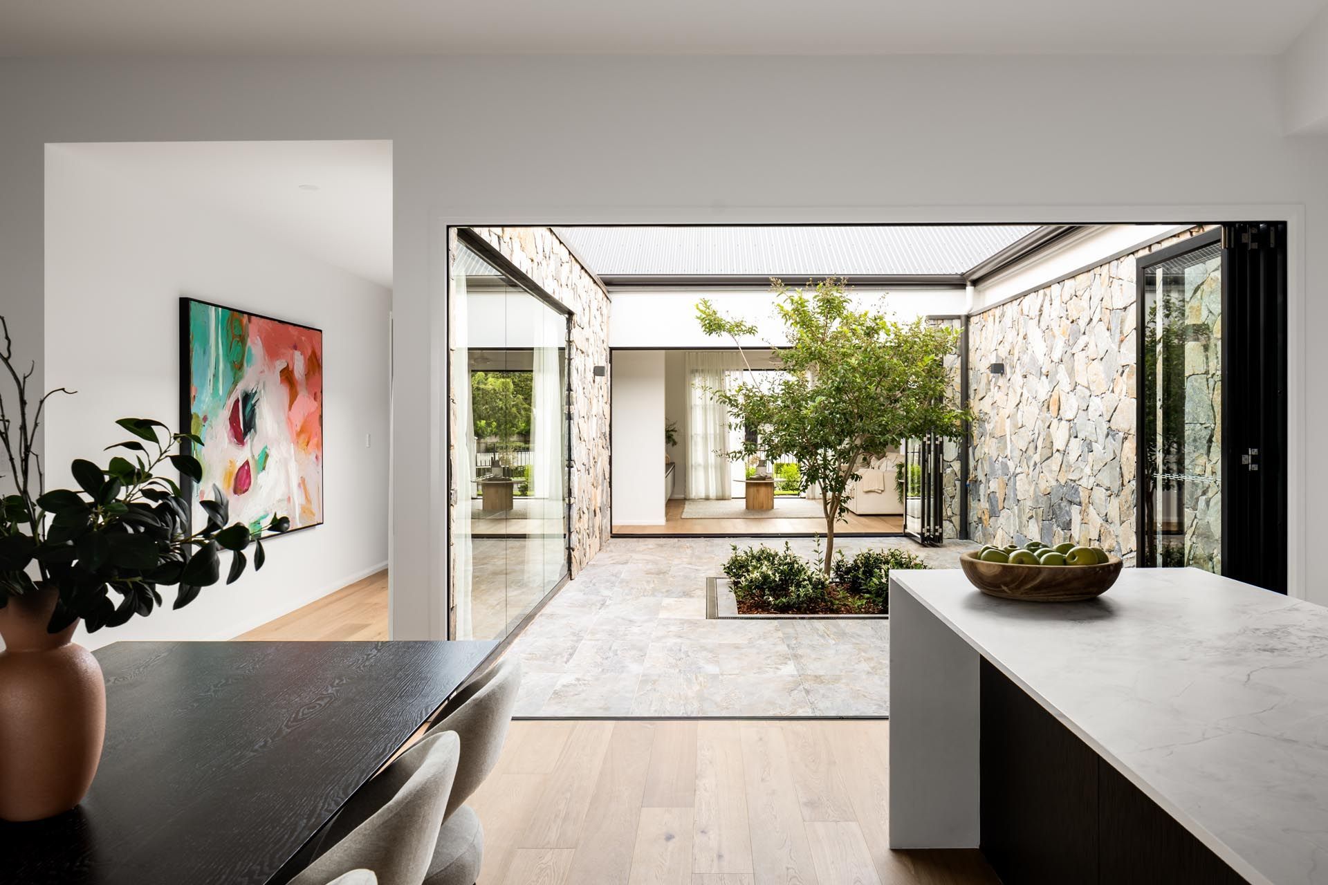A dining room and kitchen with a table and chairs and a view of a courtyard.
