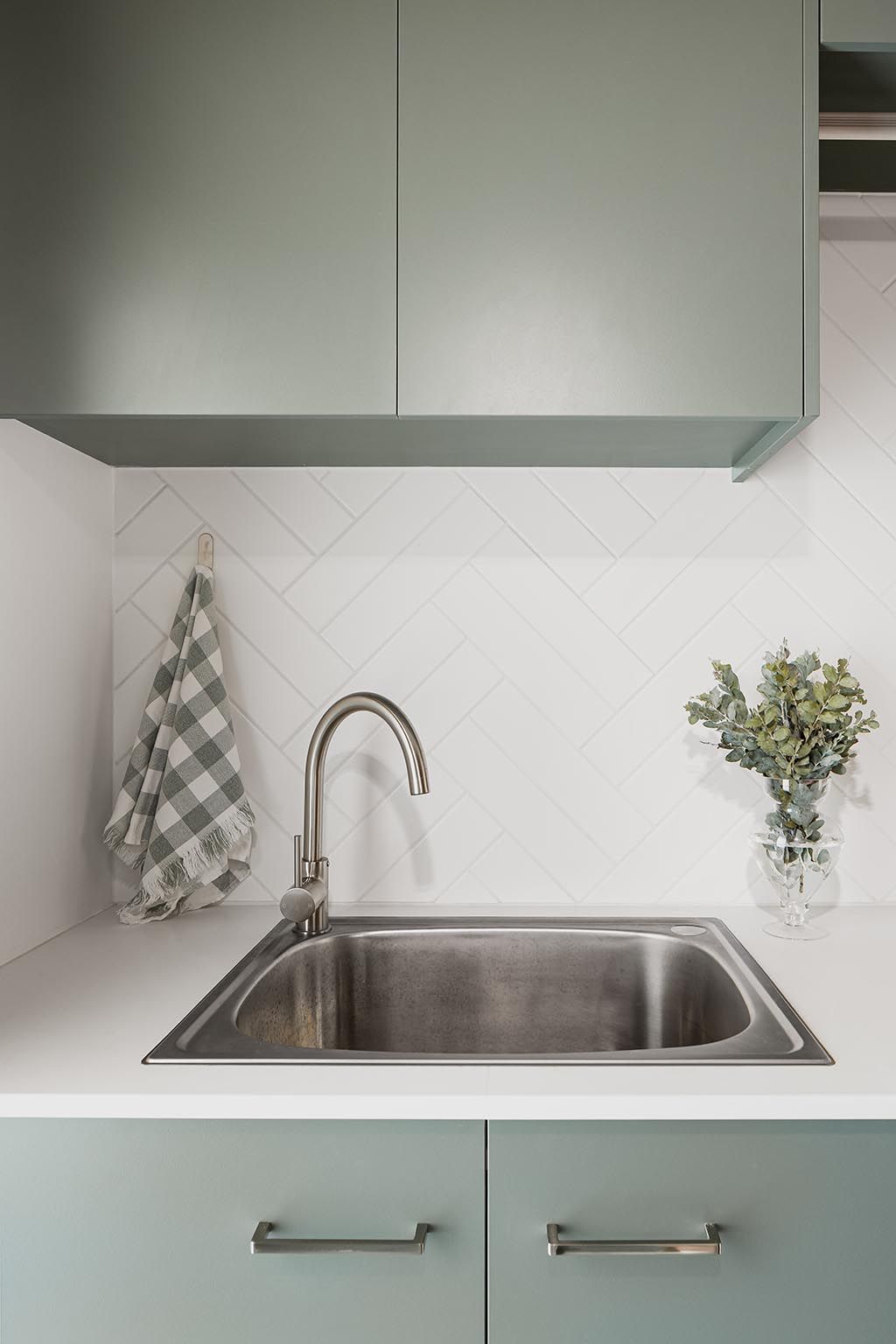 a kitchen sink with a tap and a towel hanging on the wall .