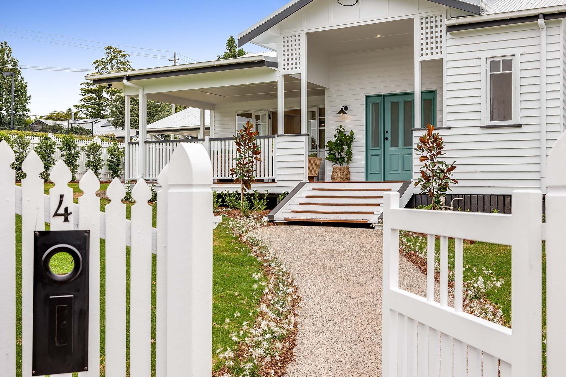 a white picket fence surrounds a white house with a blue door .