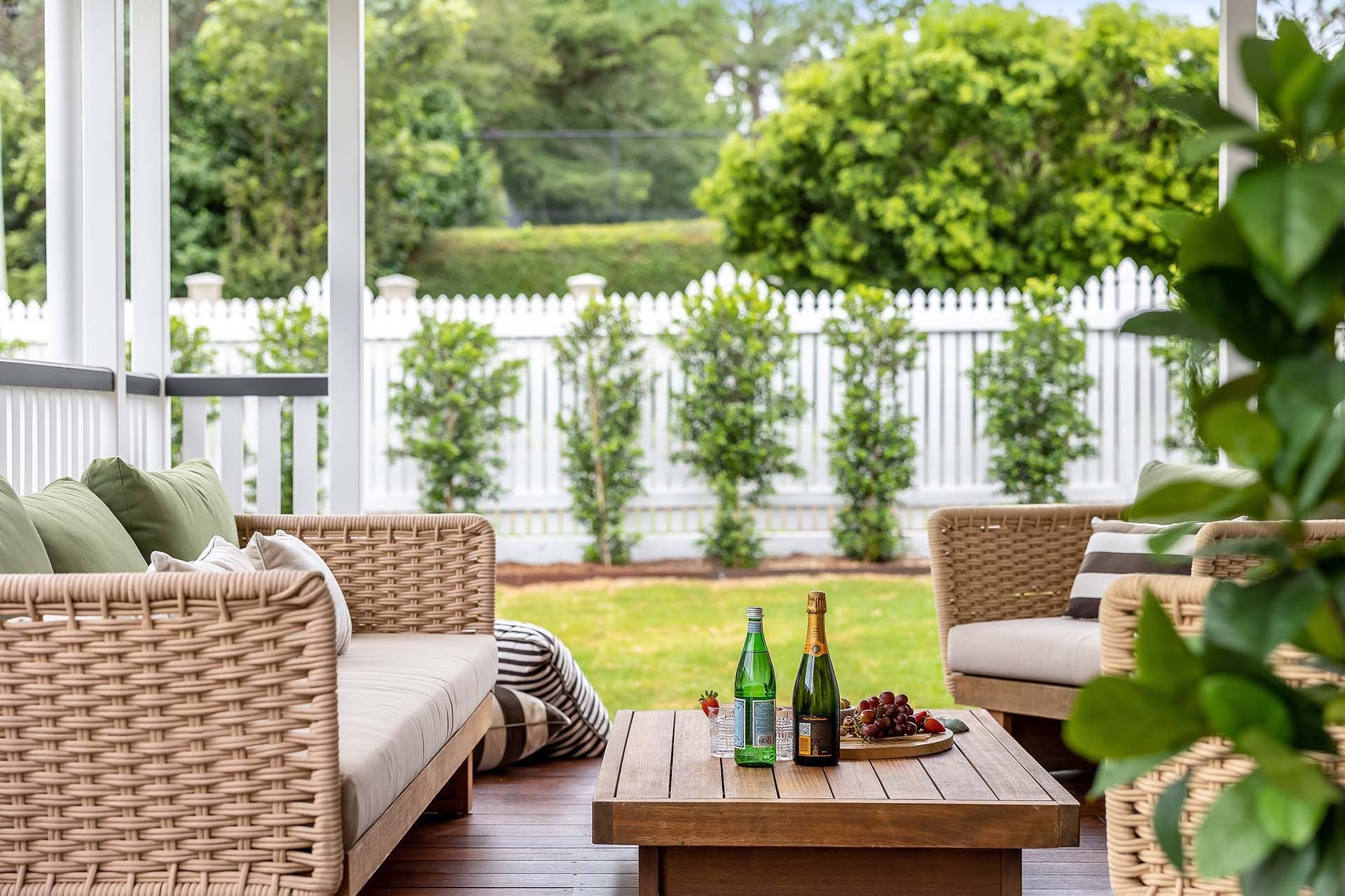 a patio with wicker furniture and a wooden table with wine bottles on it .