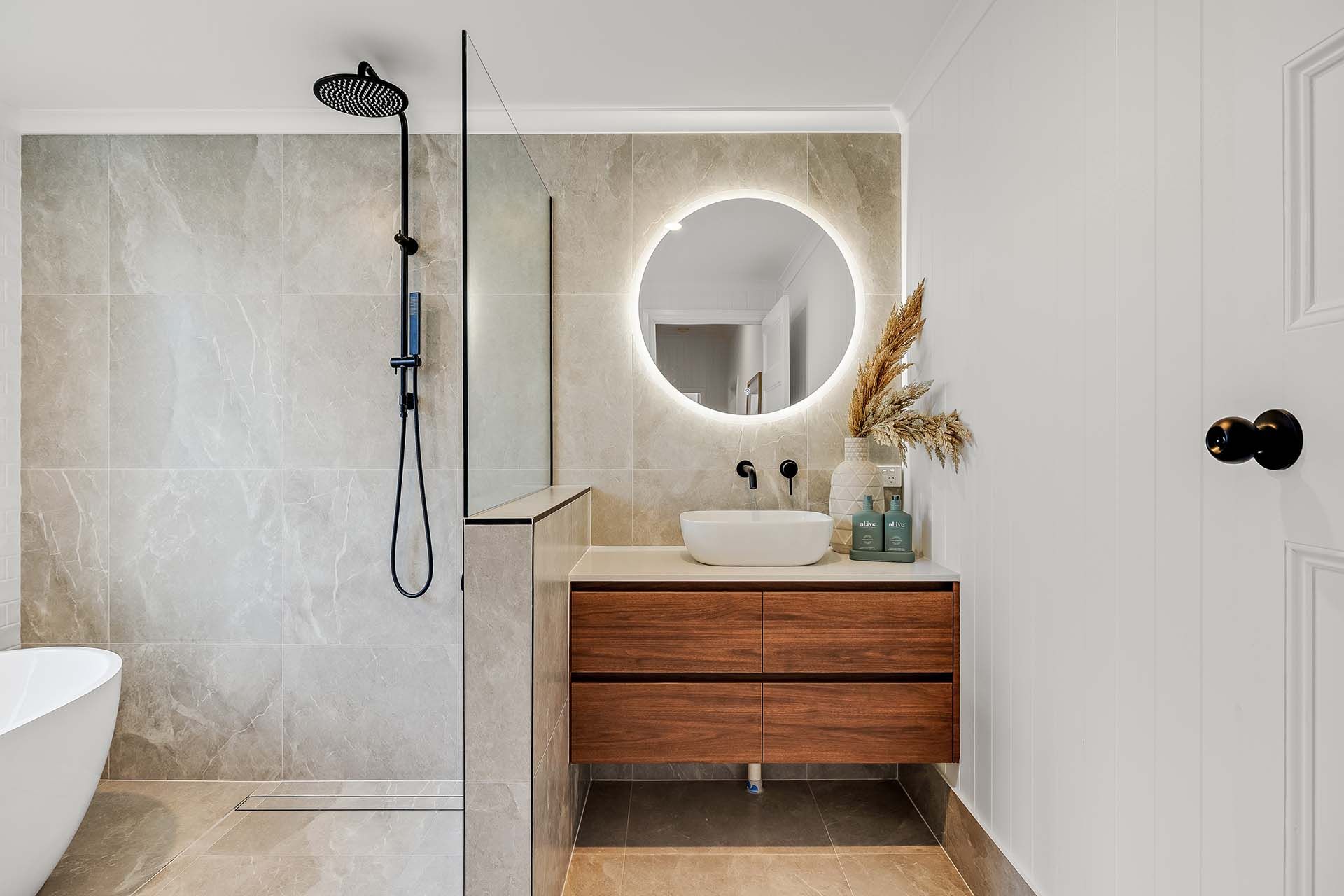 a bathroom with a sink , mirror and walk in shower .
