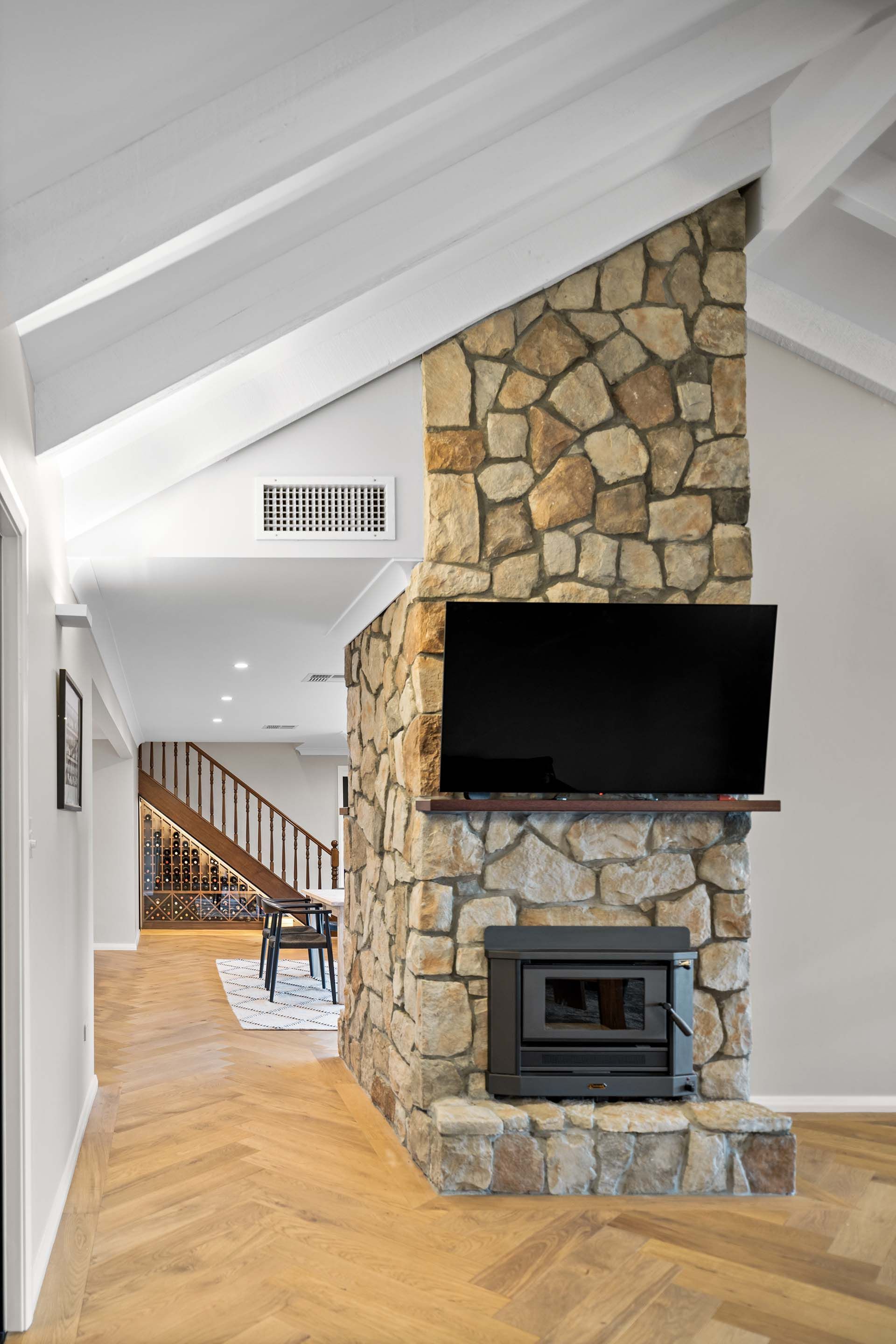 a living room with a stone fireplace and a flat screen tv .