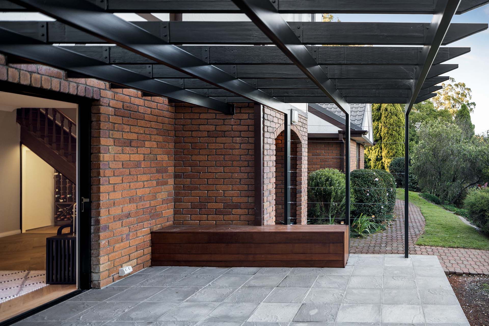 a brick house with a wooden bench under a pergola .