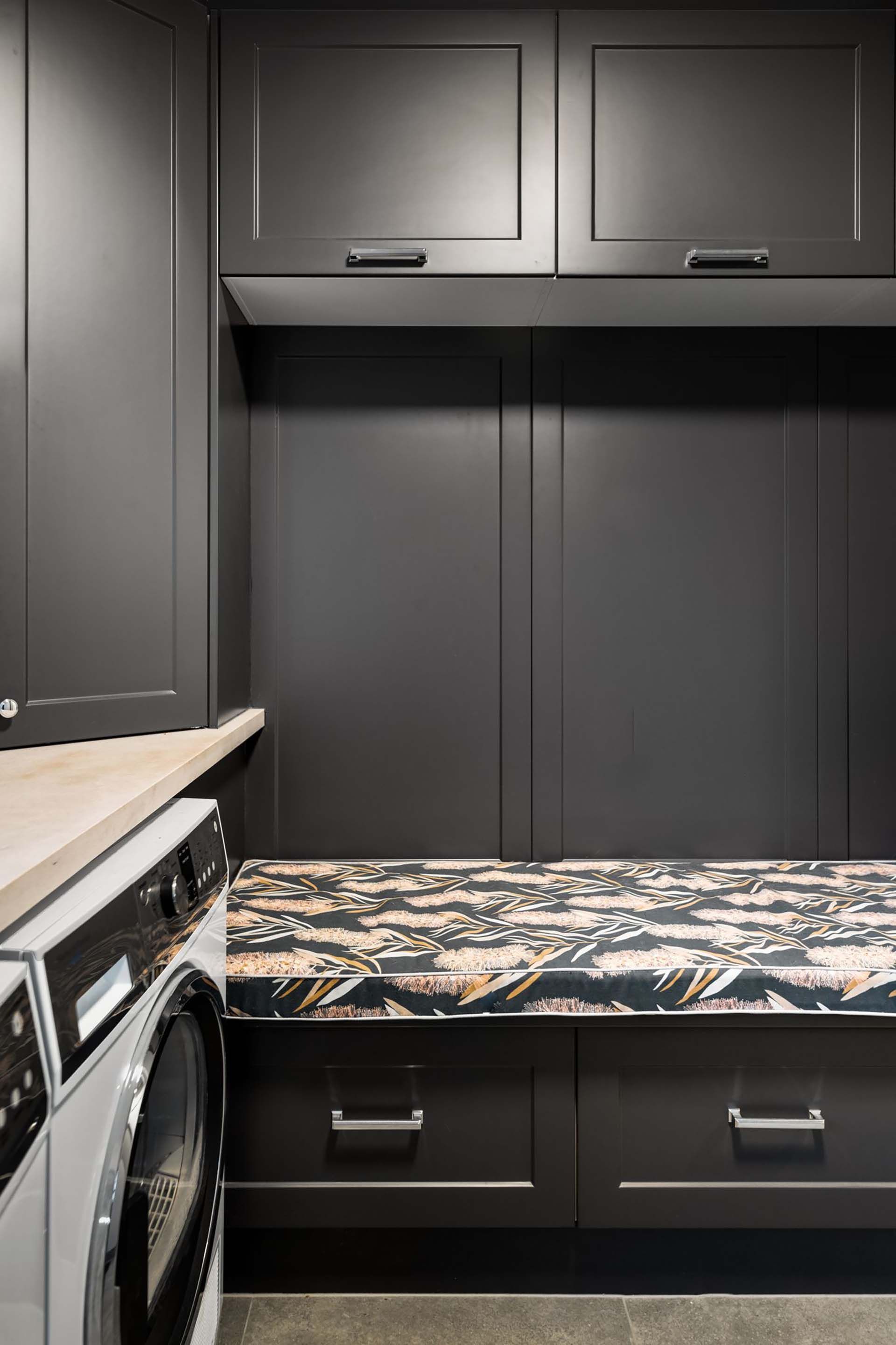 a laundry room with a washer and dryer and a bench .