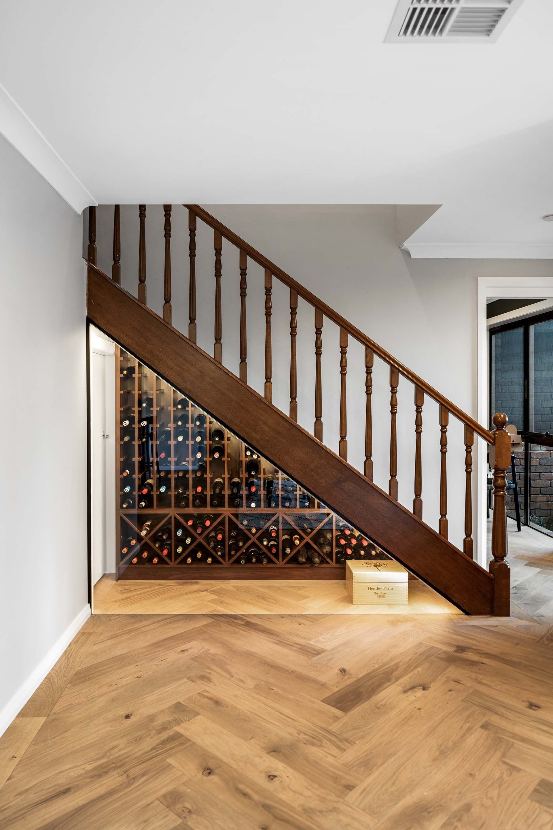 a wooden staircase with a wine rack underneath it .
