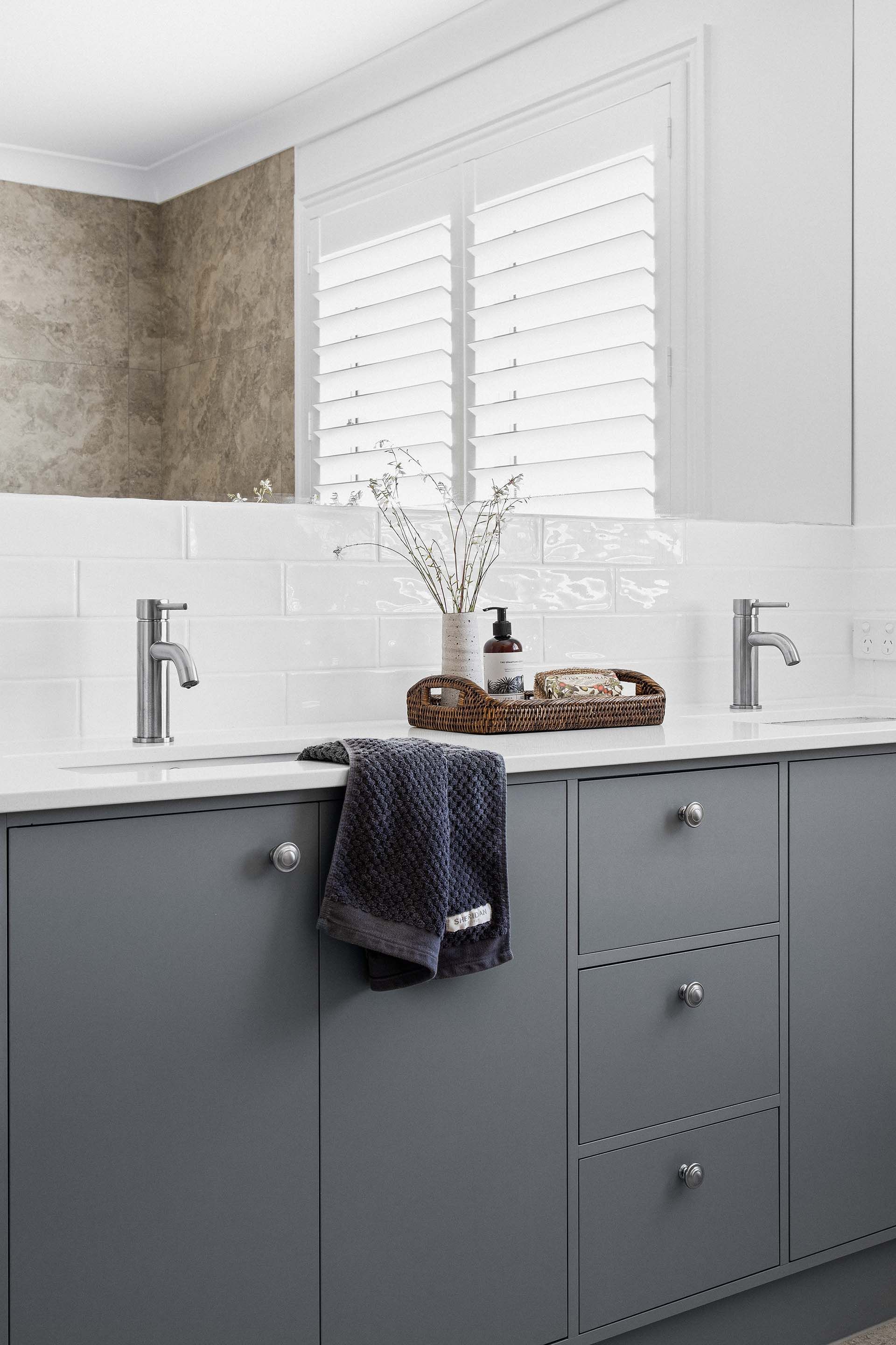a bathroom with two sinks and a window with shutters .