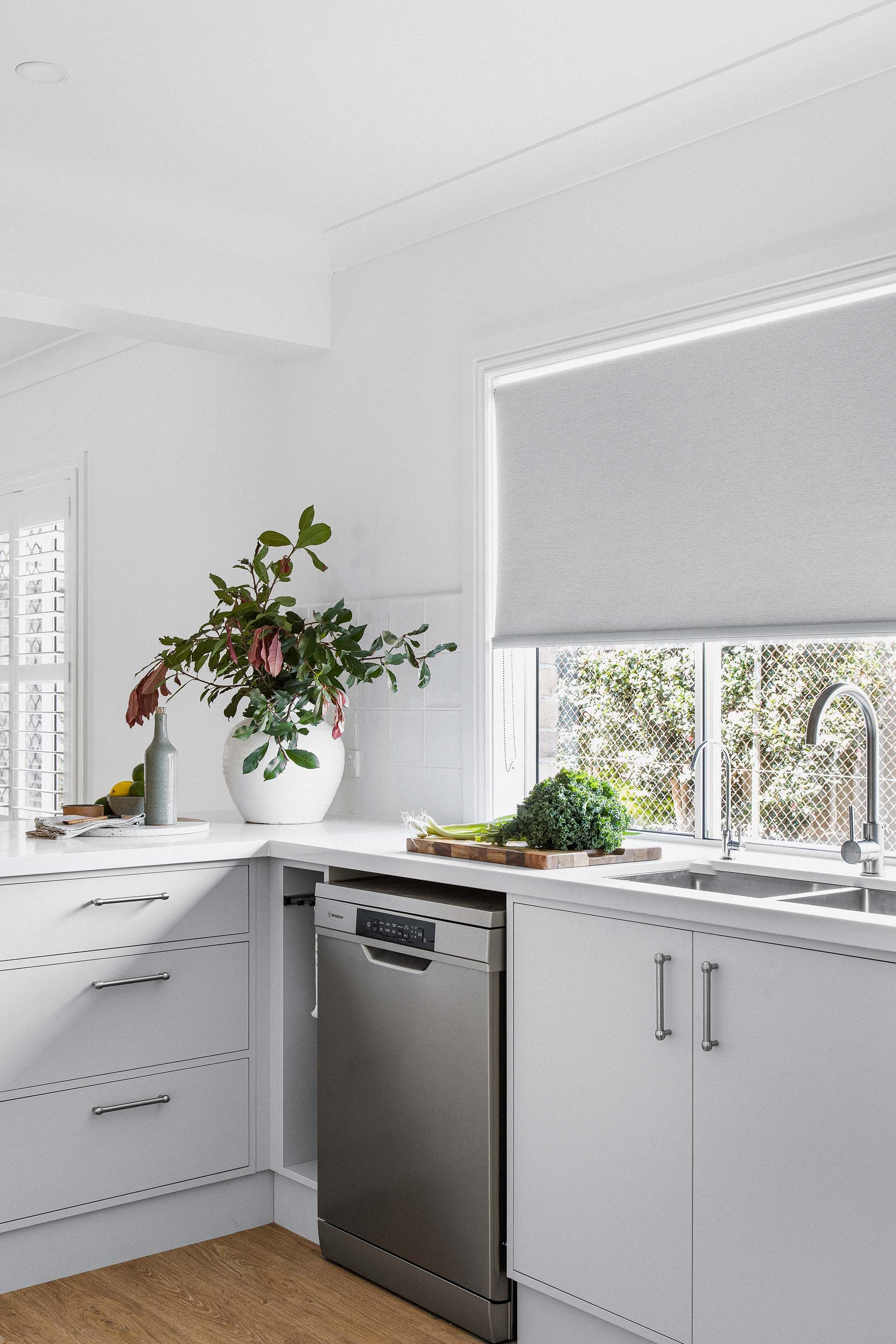 a kitchen with white cabinets , a stainless steel dishwasher , a sink , and a window .
