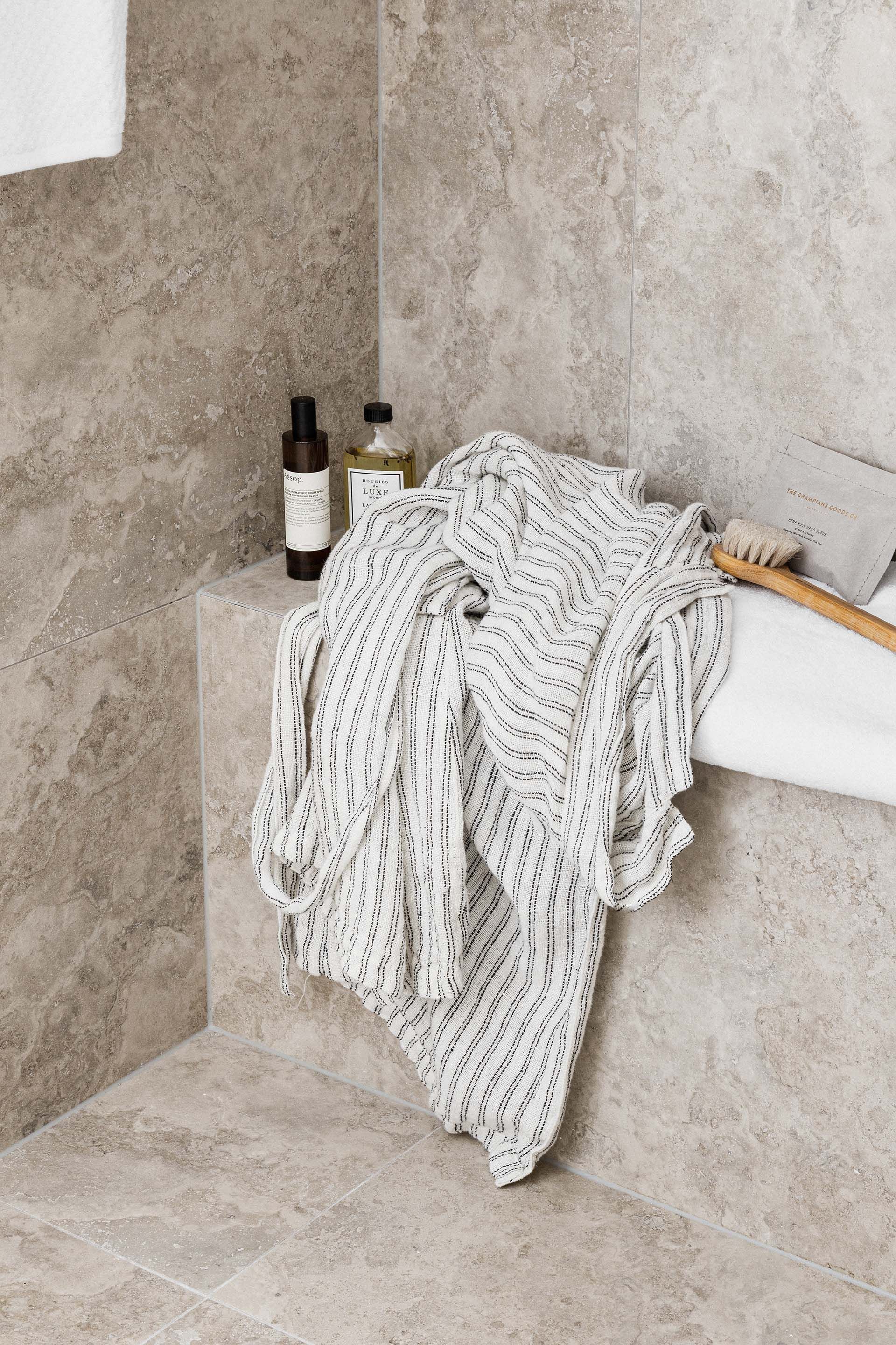 a blanket is sitting on a ledge in a bathroom next to a bathtub .