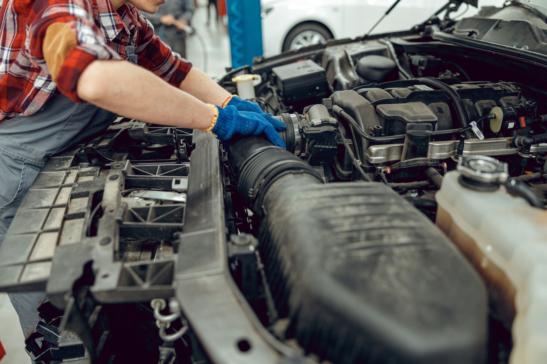 A man is working on the engine of a car in a garage.