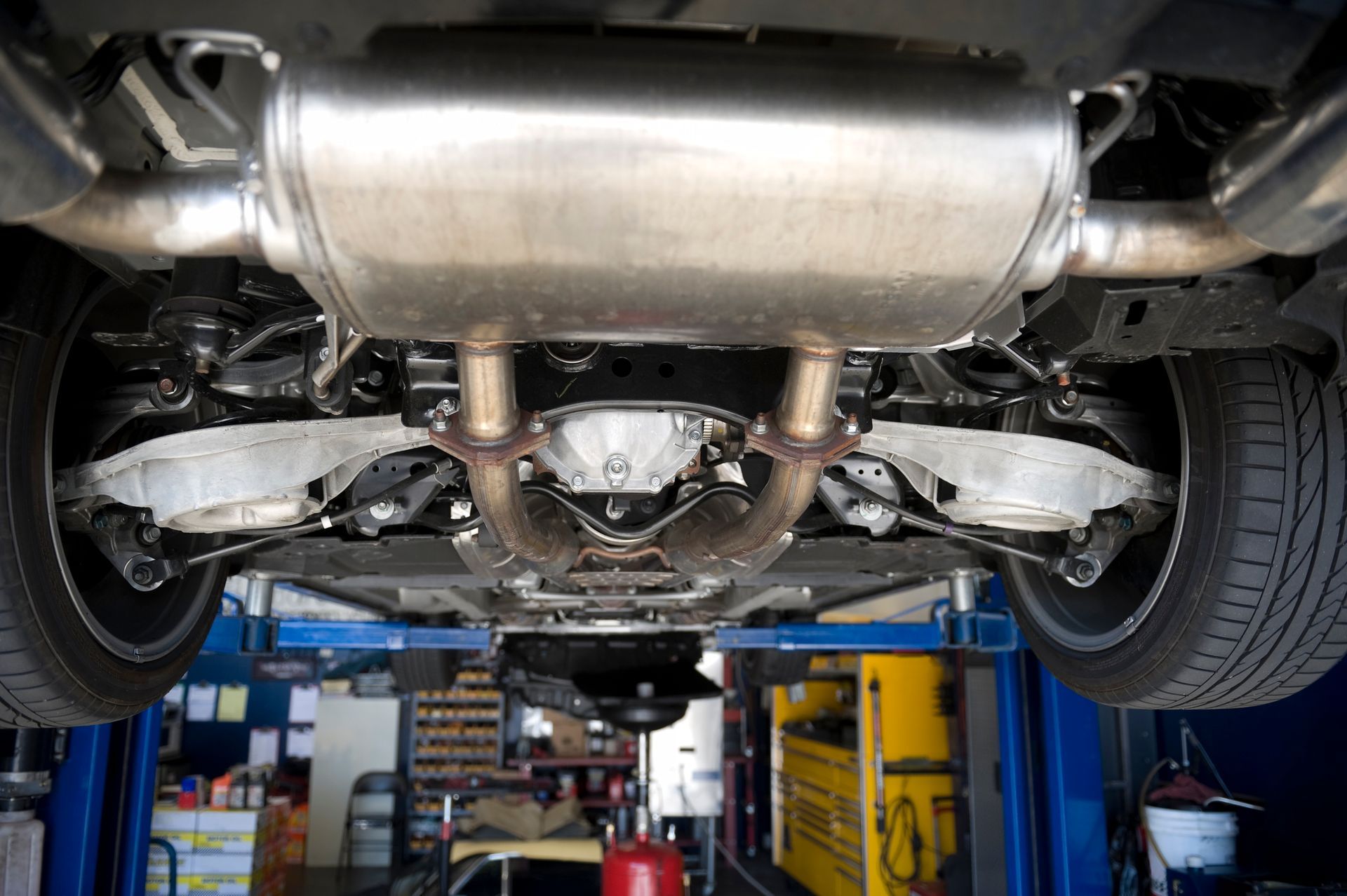The underside of a car on a lift in a garage.