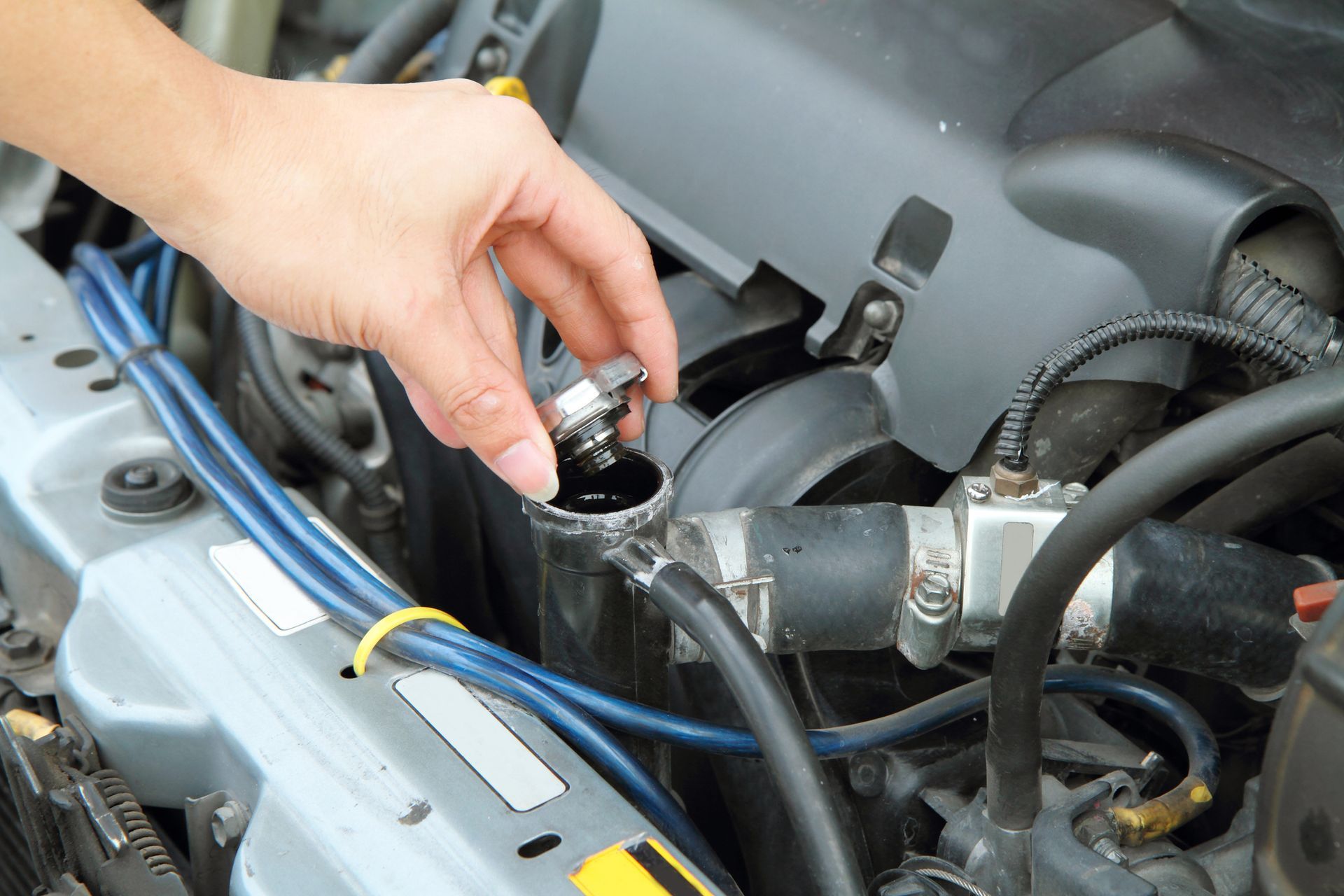 A person is checking the cooling system of a car.
