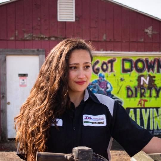 A woman stands in front of a sign that says
