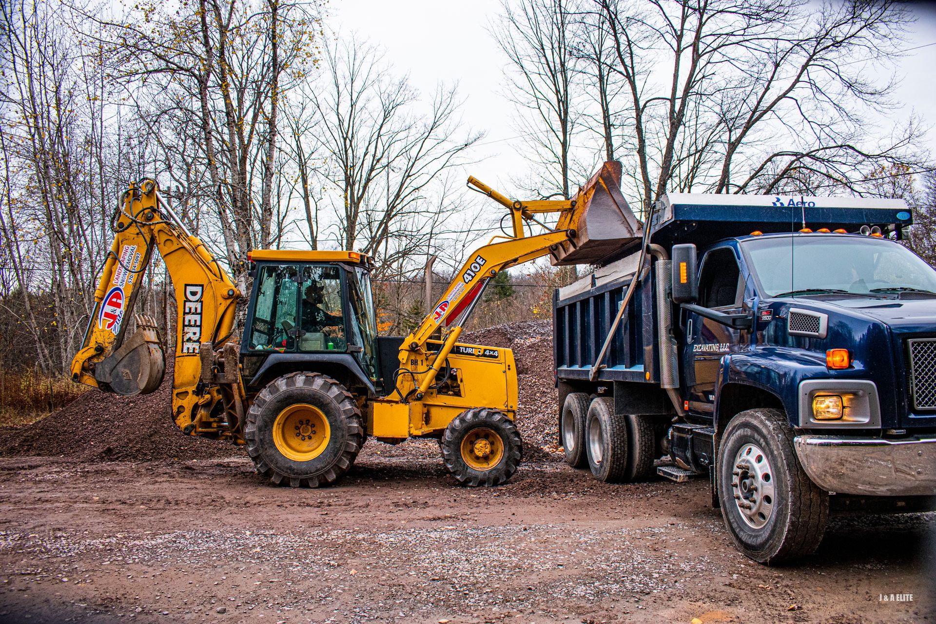 A yellow excavator is loading dirt into a dump truck.