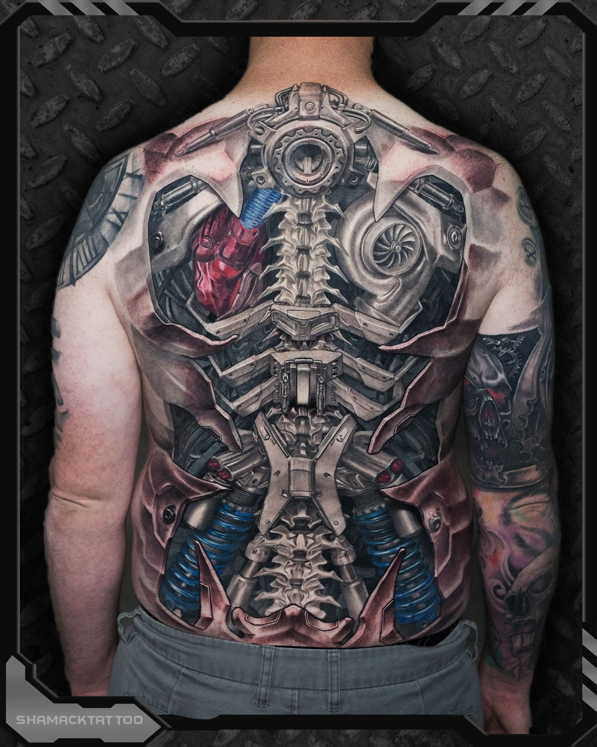 Biomechanical back tattoo by Shamack showing spine-integrated metal structure and realistic 3D mechanical anatomy.