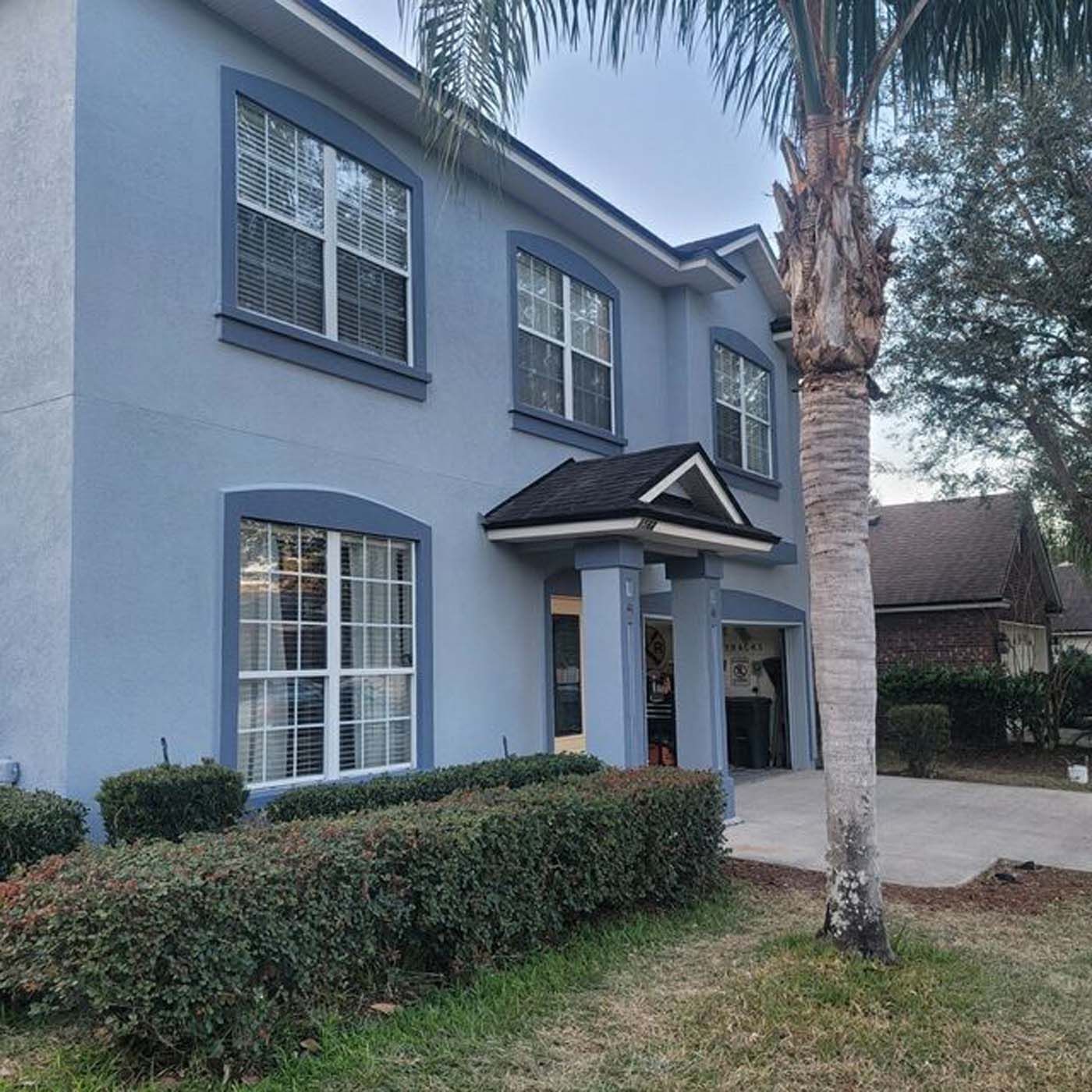 A blue house with a palm tree in front of it