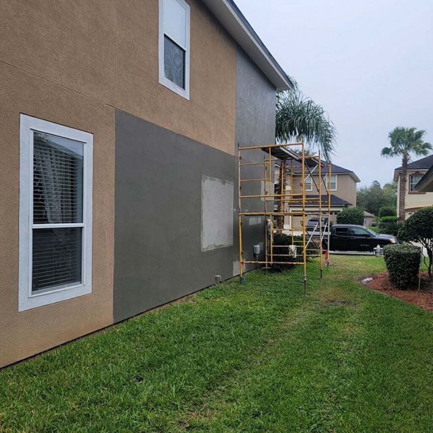 A house is being painted with a scaffolding in the backyard.