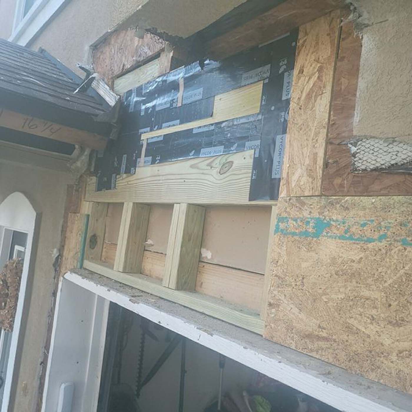 A wooden shelf is being built on the side of a building.