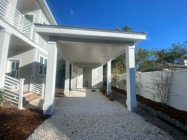 A white house with a porch and gravel in front of it.