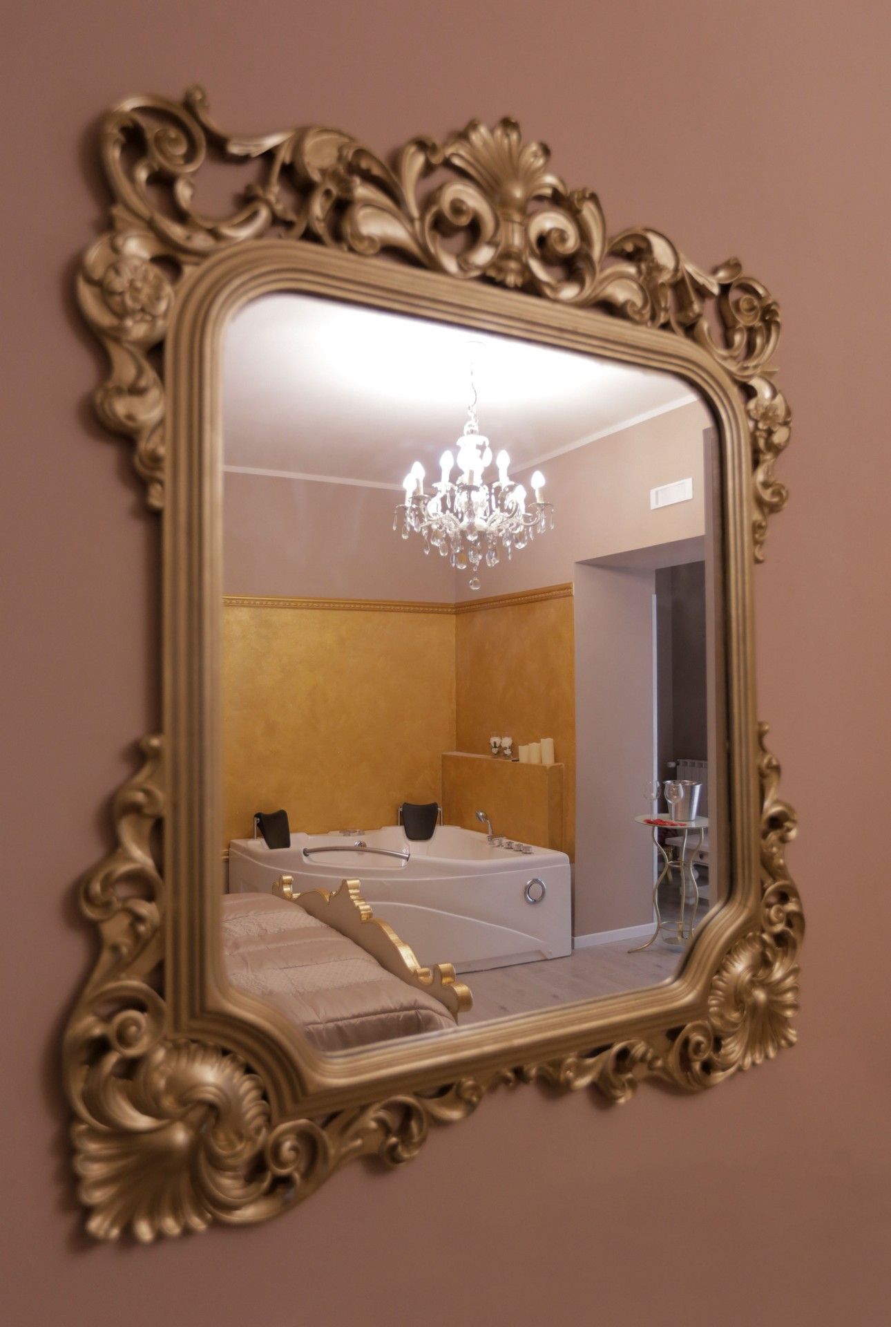 Un grande specchio con una cornice dorata è appeso a una parete.