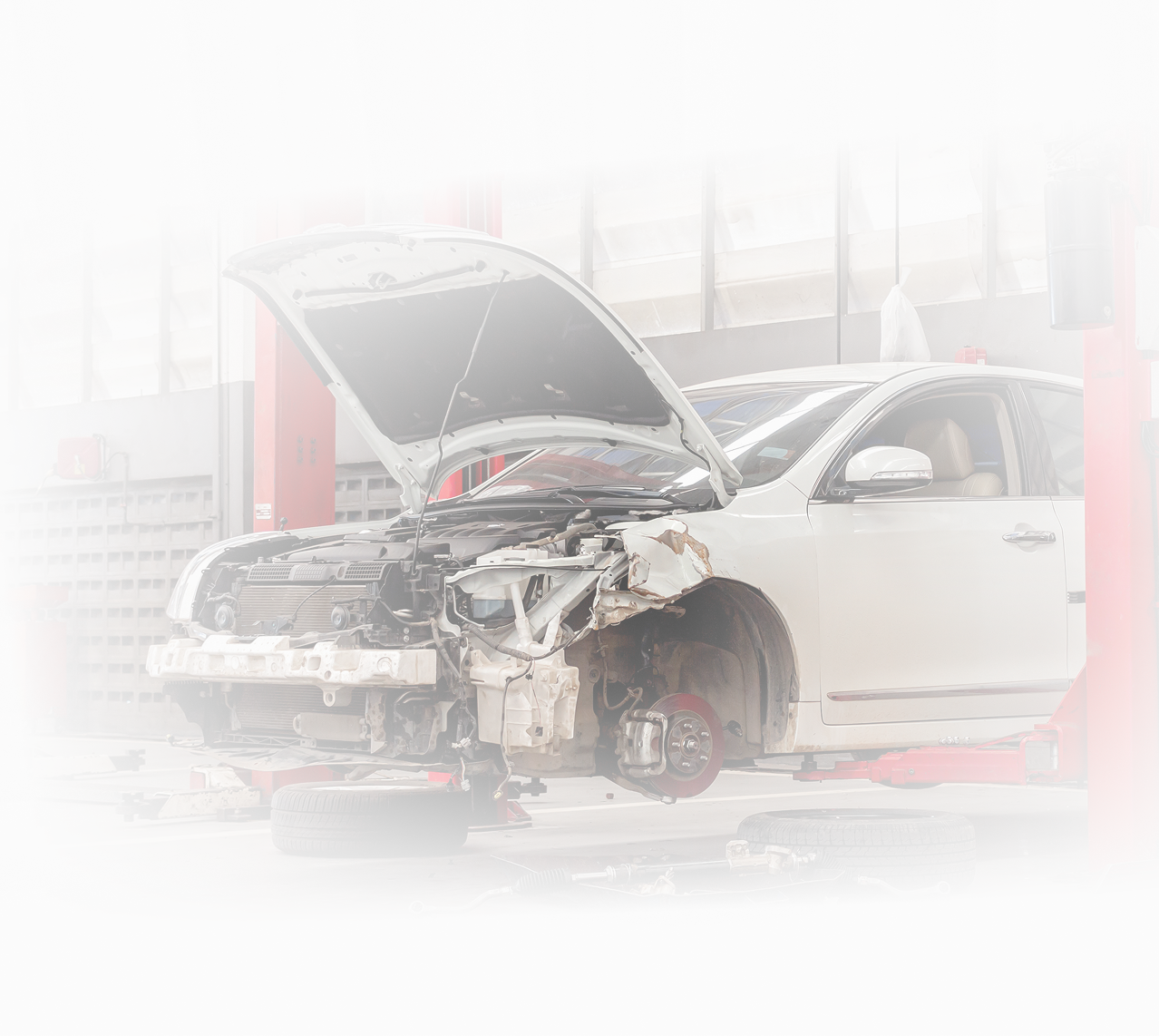 A white car with its hood open is sitting on a lift in a garage. | Dawson's Auto Care