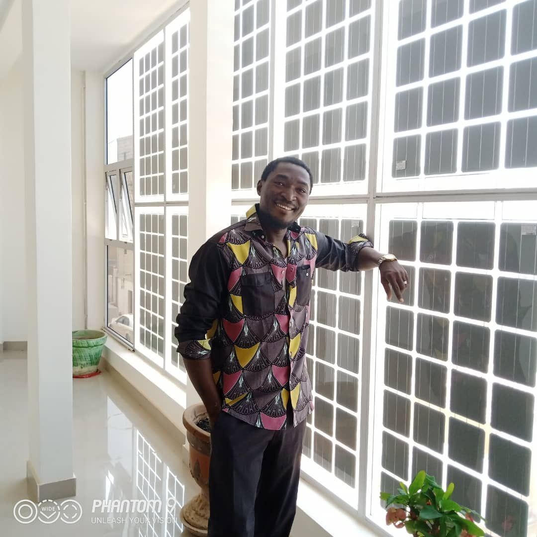 A man in a colorful shirt is leaning against a window