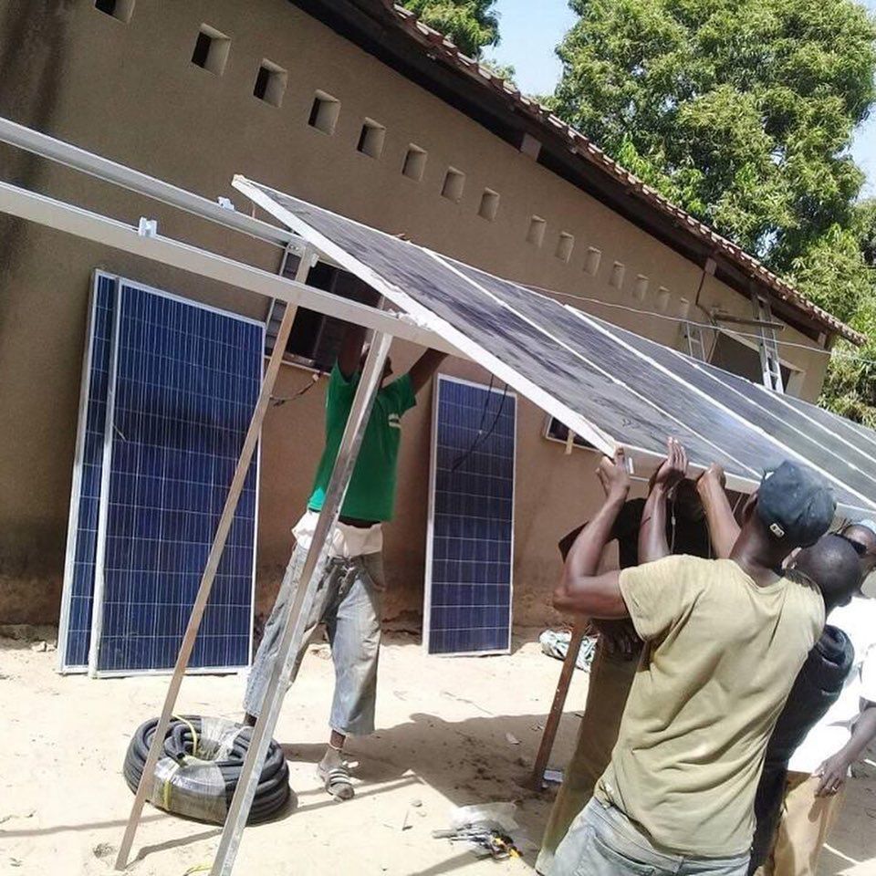 A group of men are installing solar panels in front of a building