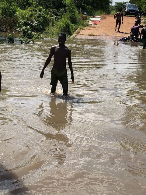 A man is walking through a flooded road.