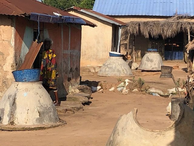 A woman is standing in front of a building in a village.