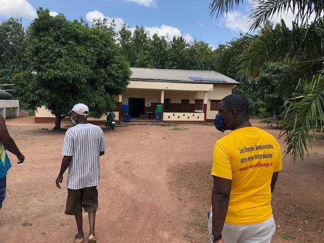 A man in a yellow shirt is standing in front of a building