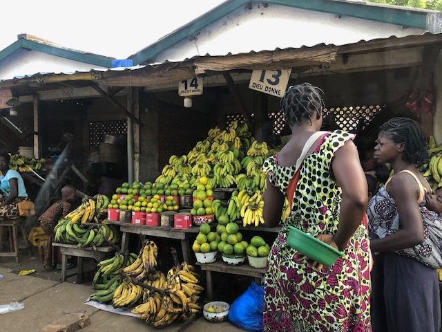 A woman standing in front of a fruit stand with the number 13 on it