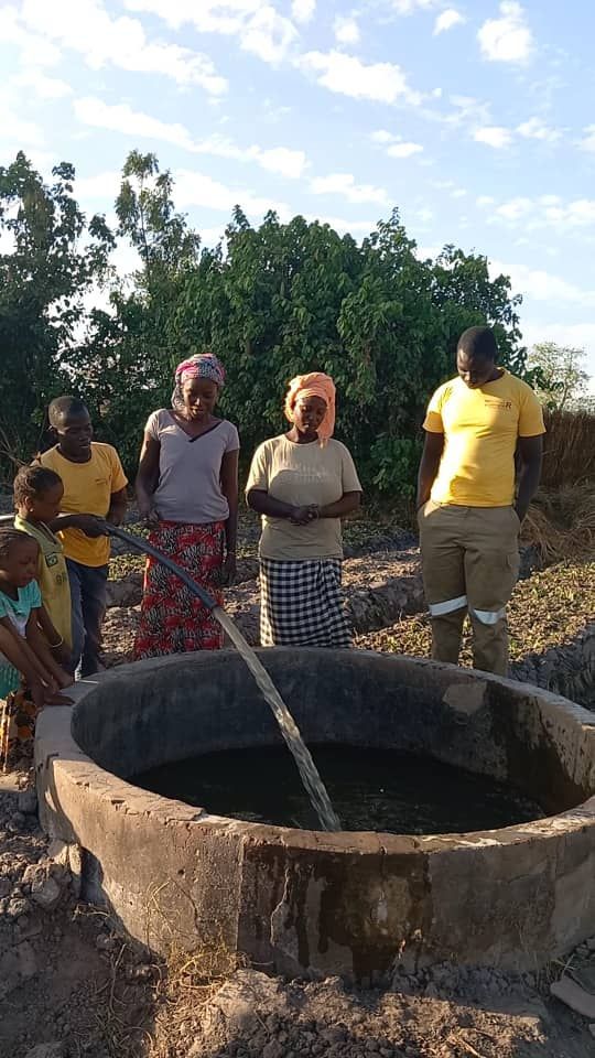 A group of people are standing around a large bowl of water.