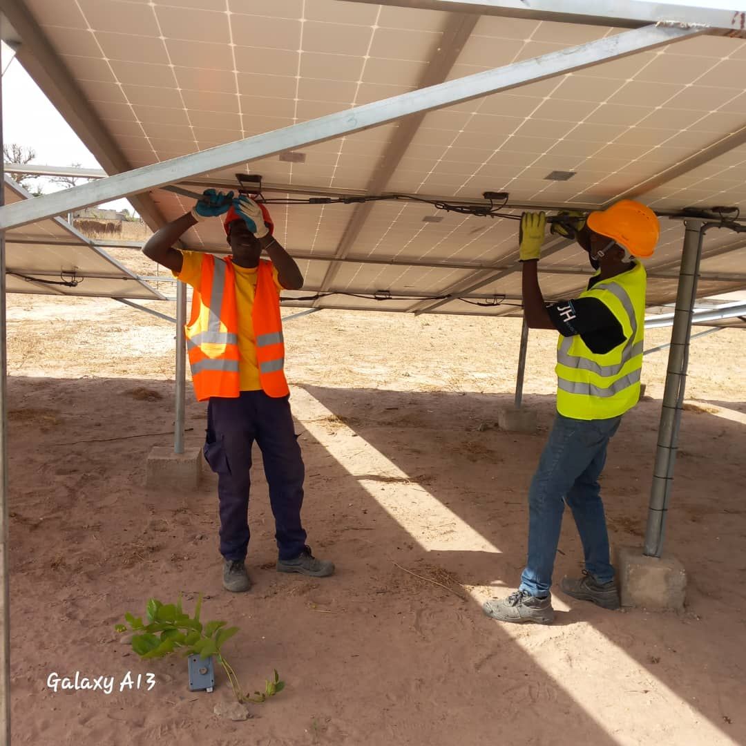 Two men working on a solar panel with a galaxy a13 in the background