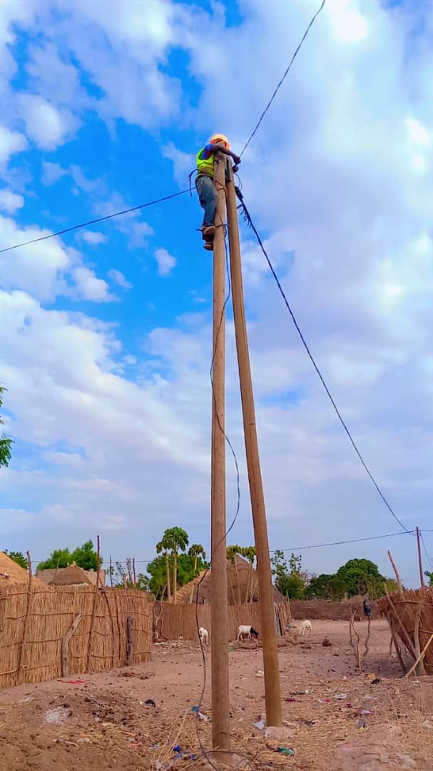 A man is standing on top of a wooden pole.