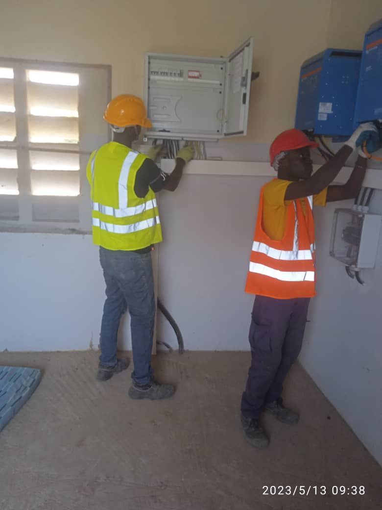 Two men wearing hard hats are working on a wall