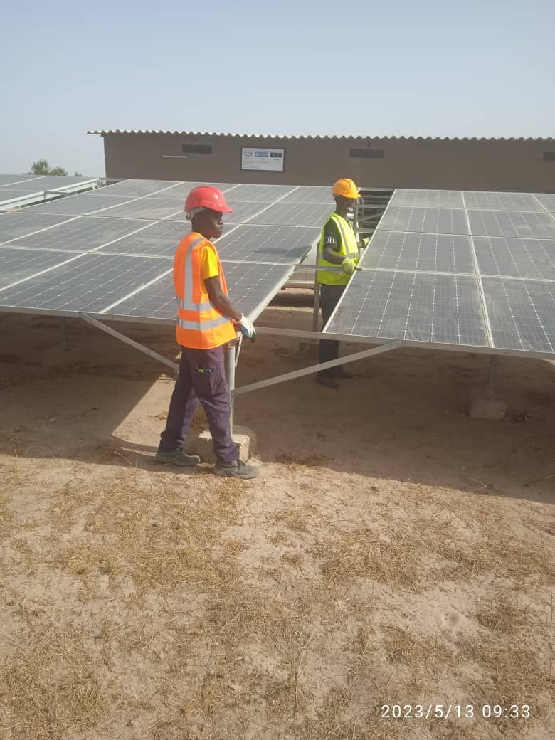 Two men are working on a solar panel on top of a building.