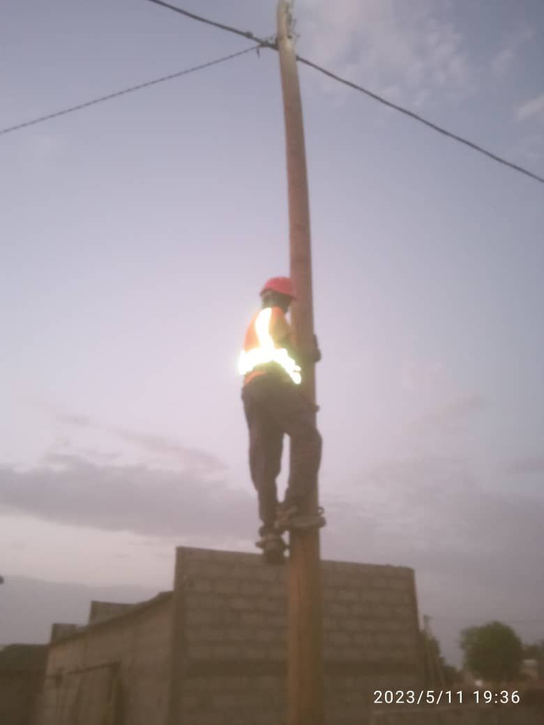 A man is standing on top of a telephone pole