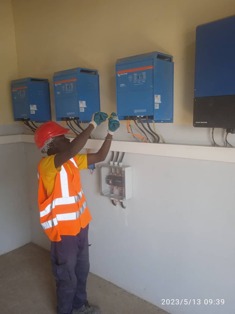 A man in an orange vest and hard hat is working on a wall.