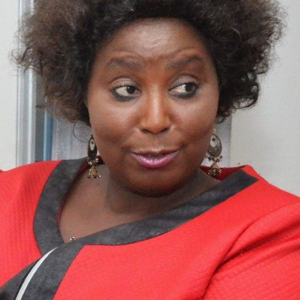 A woman wearing a red dress and earrings looks at the camera