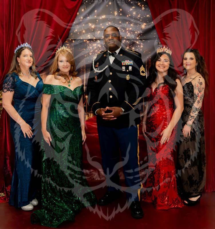 A person in a military dress uniform stands with four people in formal evening gowns against a red curtain background.