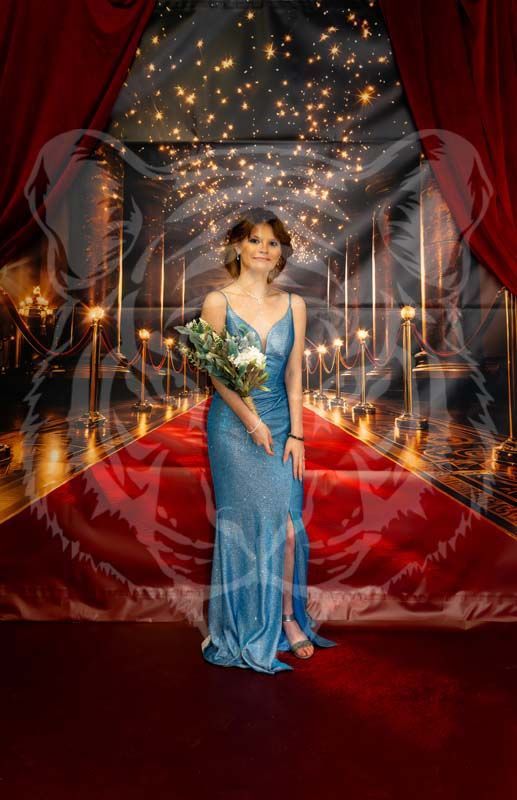 A person in a blue formal gown holds flowers on a red carpet path leading through a starry corridor.